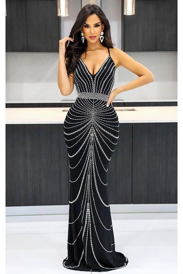 Woman wearing a black evening gown with silver embellishments in a studio setting.