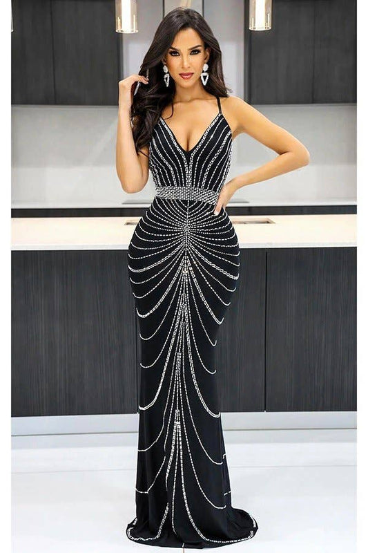 Woman wearing a black evening gown with silver embellishments in a studio setting.